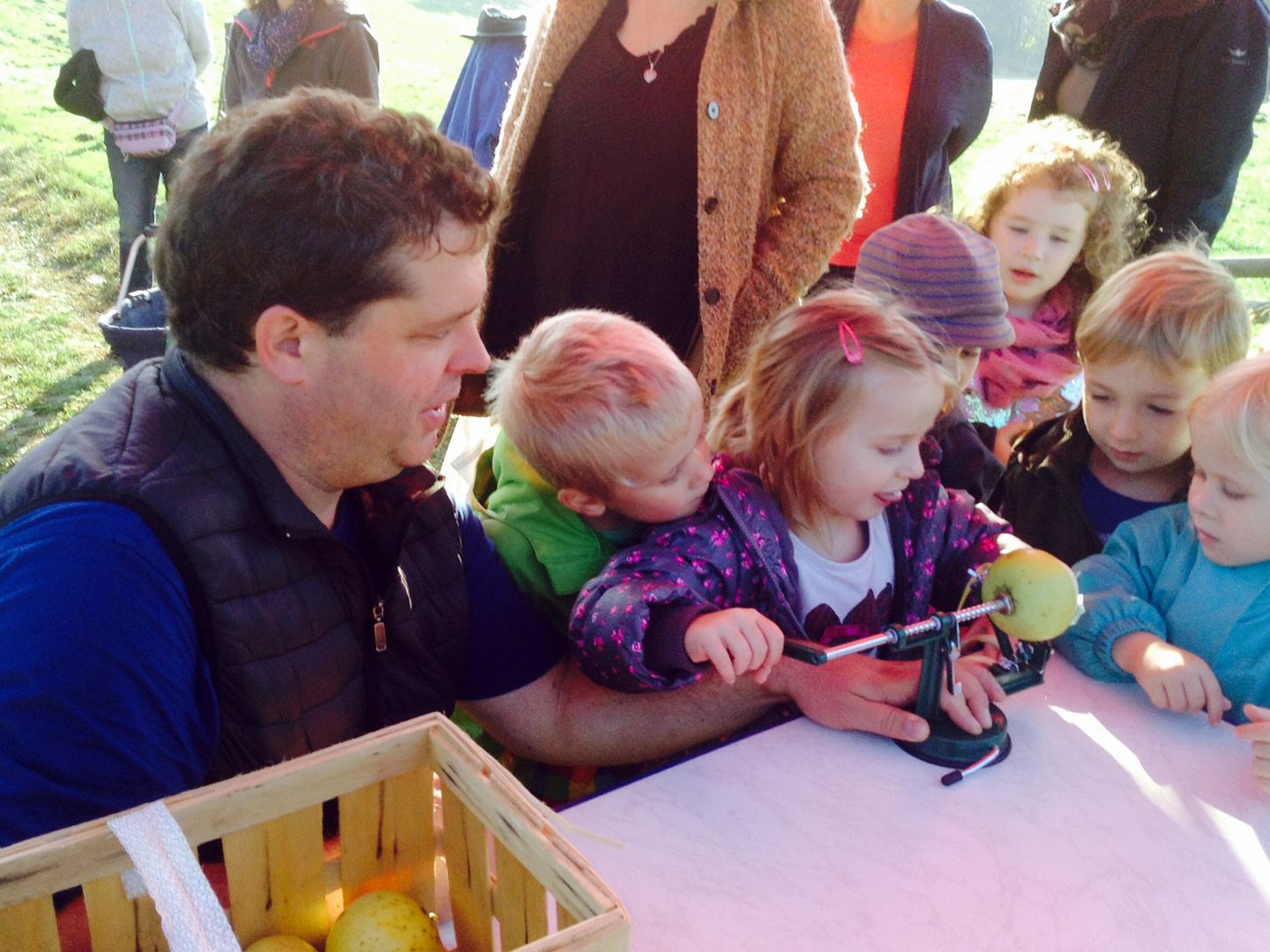 Naturpädagoge mit Kindergartenkindern beim Apfelschälen